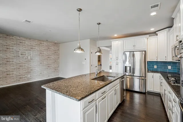 a kitchen with stainless steel appliances granite countertop a sink a stove and a refrigerator