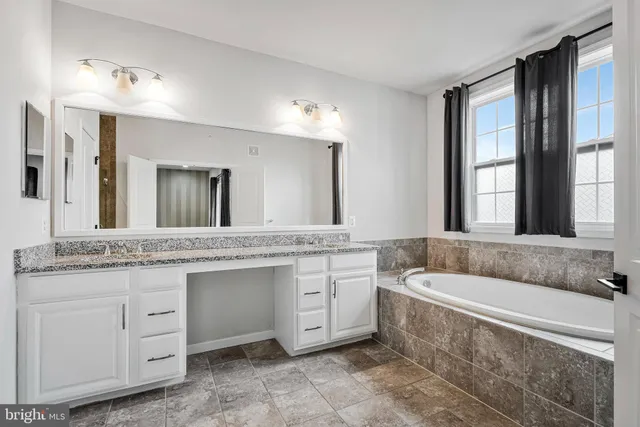 a spacious bathroom with a granite countertop tub sink and mirror