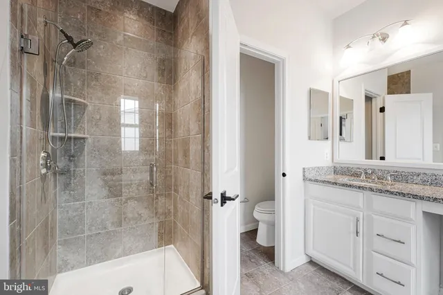 a bathroom with a granite countertop sink a toilet and shower