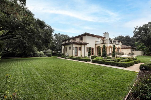 a view of a house with a big yard potted plants and large tree