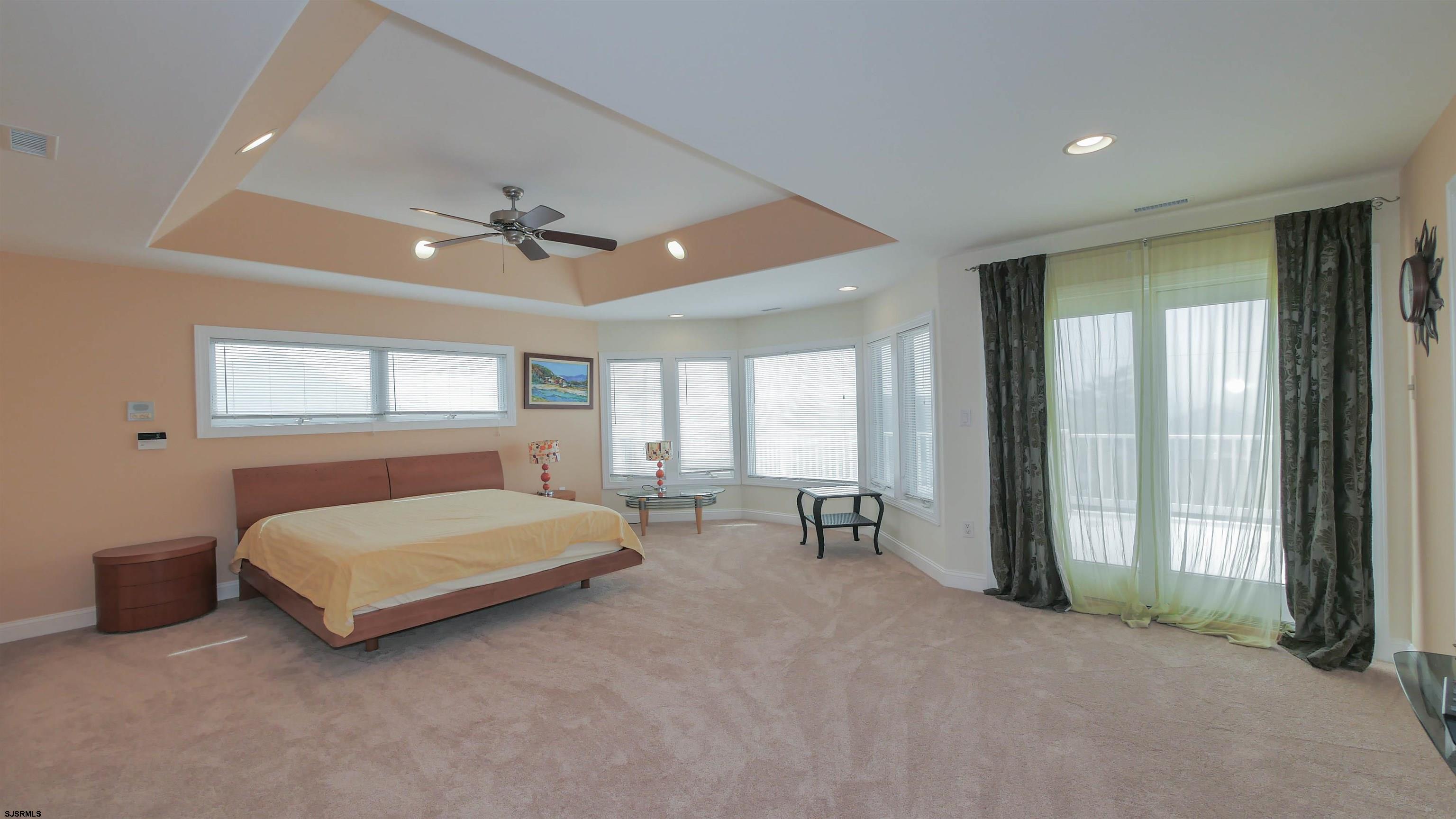 229 8th Street North Brigantine, NJ 08203 - Photo 20 of 42 a spacious bedroom with a bed a chandelier and large window