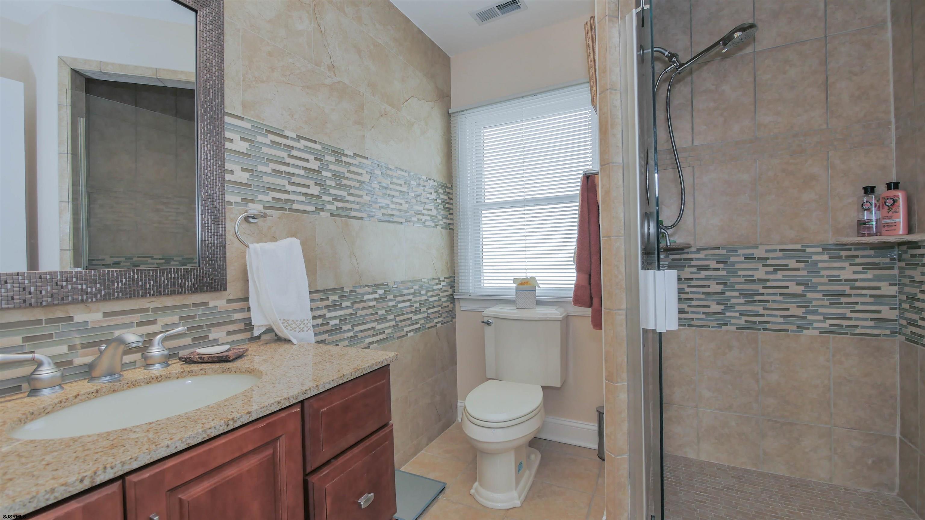 229 8th Street North Brigantine, NJ 08203 - Photo 27 of 42 a bathroom with a granite countertop toilet sink and mirror