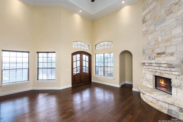 an empty room with windows fireplace and wooden floor