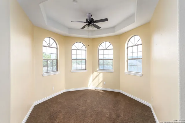 an empty room with windows and ceiling fan