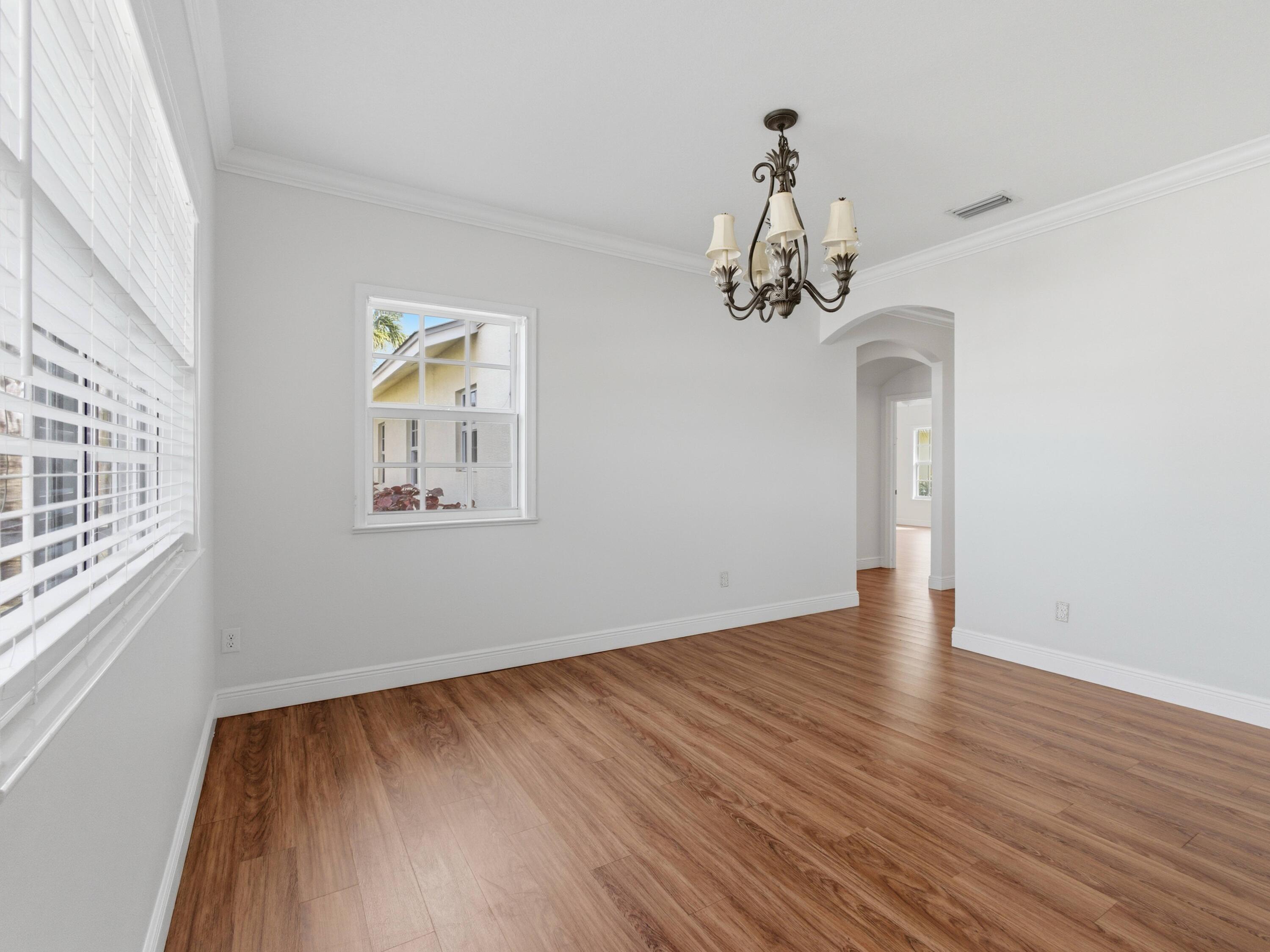 9322 Southeast Athena Street Hobe Sound, FL 33455 - Photo 16 of 68 a view of a room with wooden floor chandelier and windows