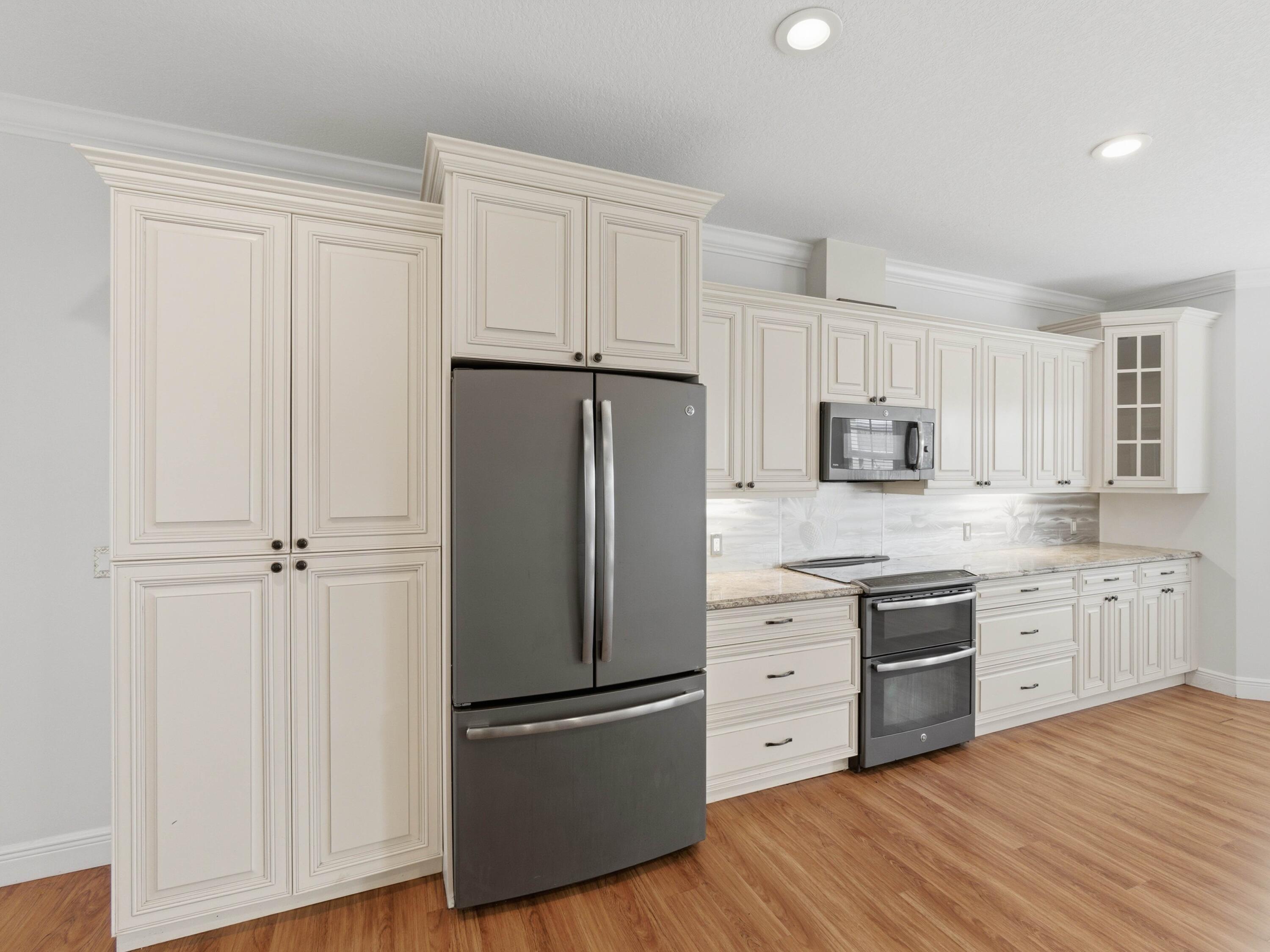 9322 Southeast Athena Street Hobe Sound, FL 33455 - Photo 24 of 68 a kitchen with white cabinets white stainless steel appliances and wooden floors