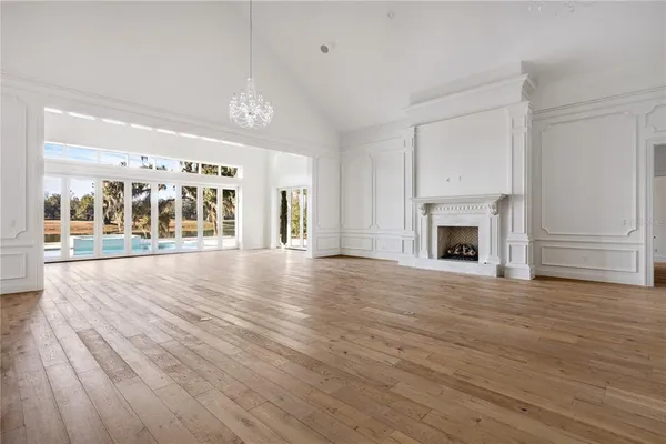 an empty room with wooden floor fireplace and windows