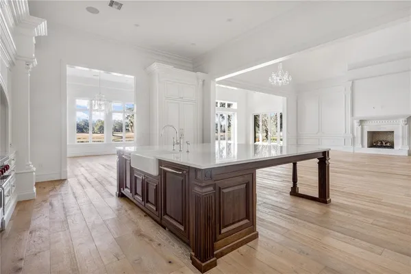 a large white kitchen with sink and wooden floor