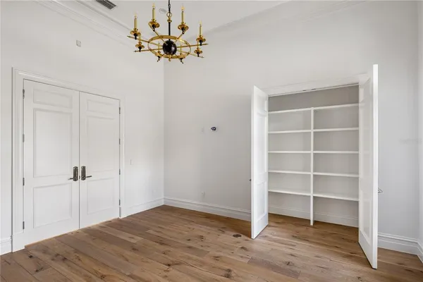 a view of a room with wooden floor closet and a chandelier fan