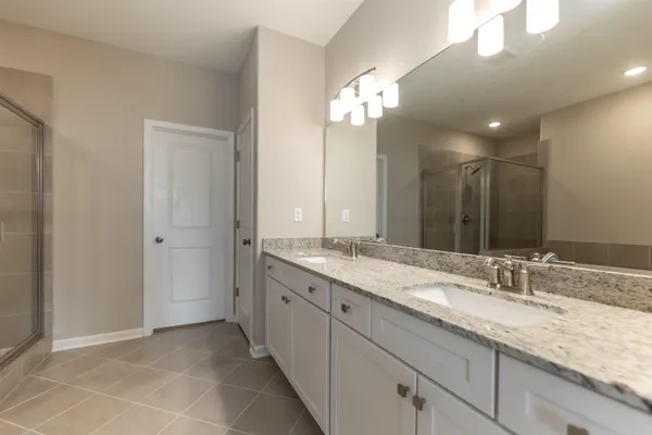 a bathroom with a granite countertop double vanity sink and a mirror