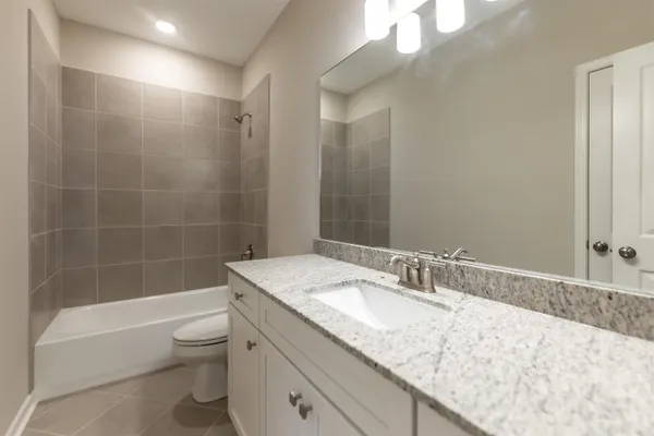 a bathroom with a granite countertop sink a toilet and bathtub