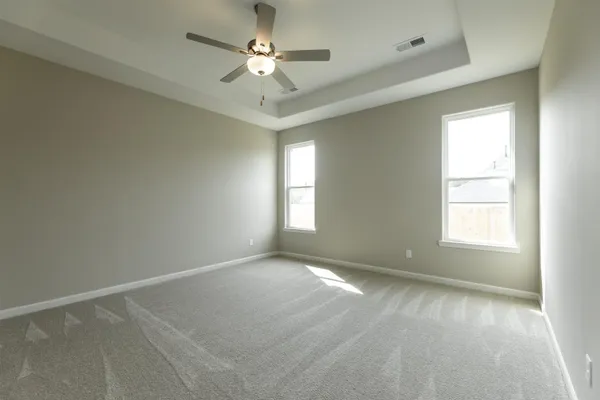 an empty room with a chandelier fan and windows