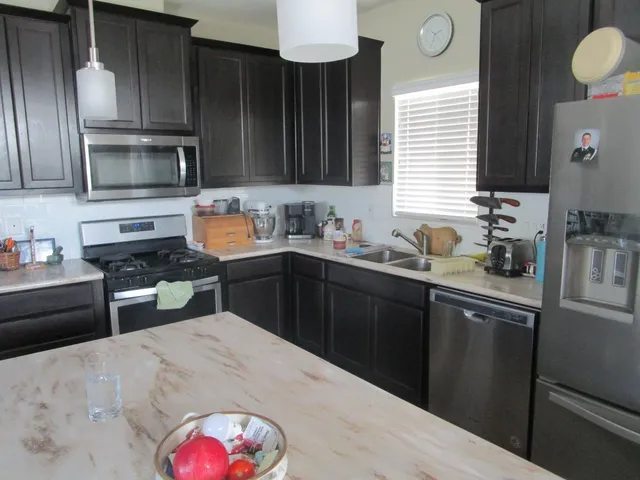 a kitchen with stainless steel appliances kitchen island granite countertop a sink dishwasher stove and cabinets