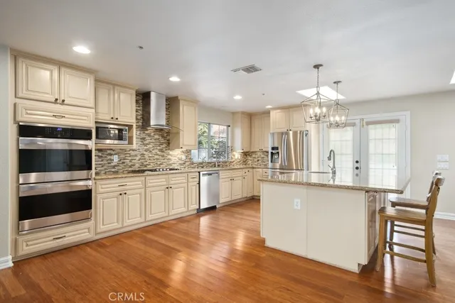 a kitchen with stainless steel appliances kitchen island granite countertop a stove a sink and white cabinets with wooden floor