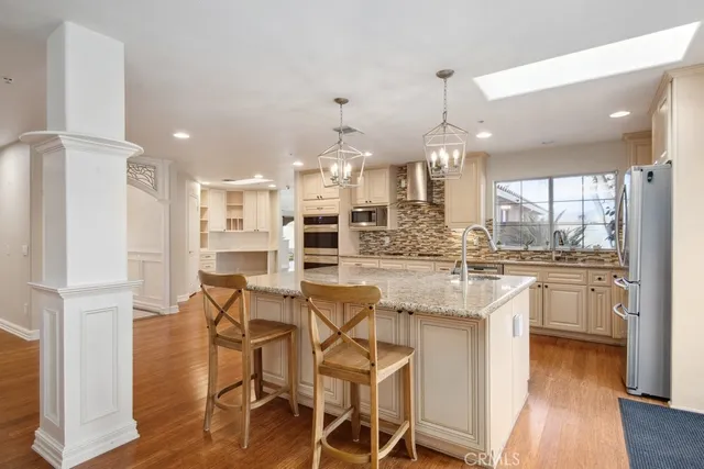 a kitchen with stainless steel appliances kitchen island granite countertop a table chairs and a refrigerator