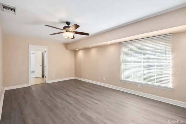 a view of an empty room with a window and a ceiling fan