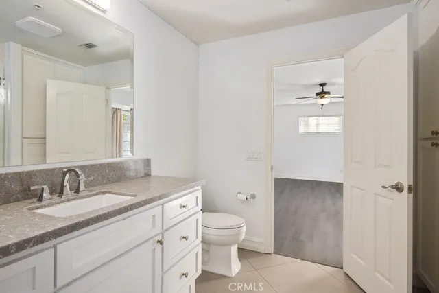 a bathroom with a granite countertop toilet a sink and a mirror