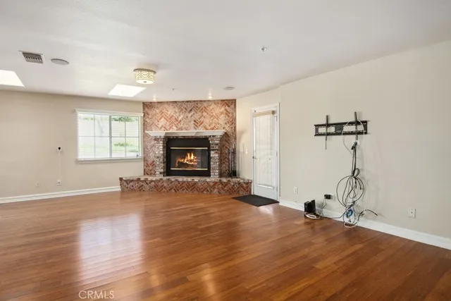 a view of empty room with wooden floor fireplace and windows