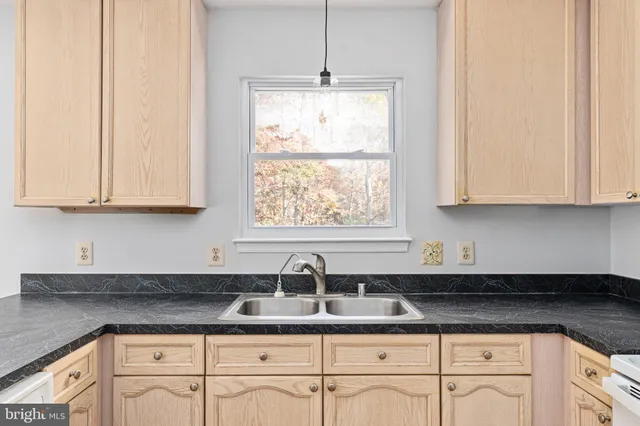 a kitchen with stainless steel appliances granite countertop white cabinets and a window