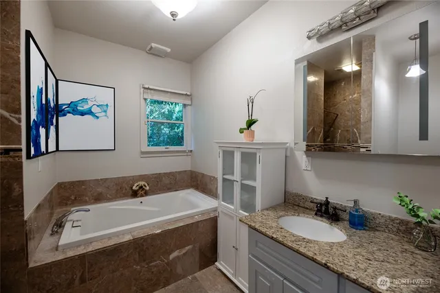 a bathroom with a granite countertop tub sink and mirror