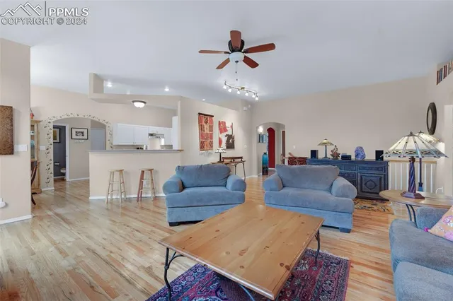a living room with furniture kitchen view and a wooden floor