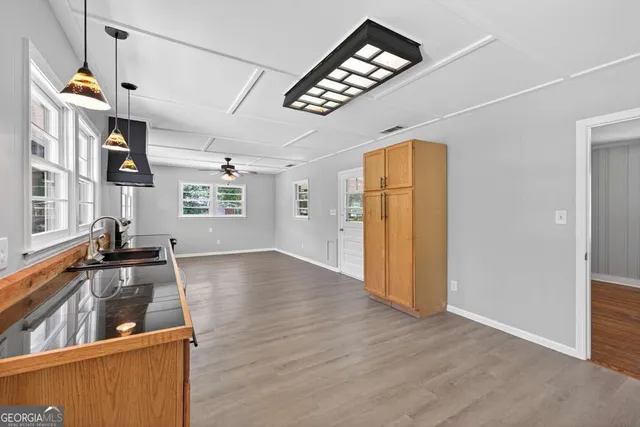 a view of a livingroom with a ceiling fan wooden floor and a ceiling fan