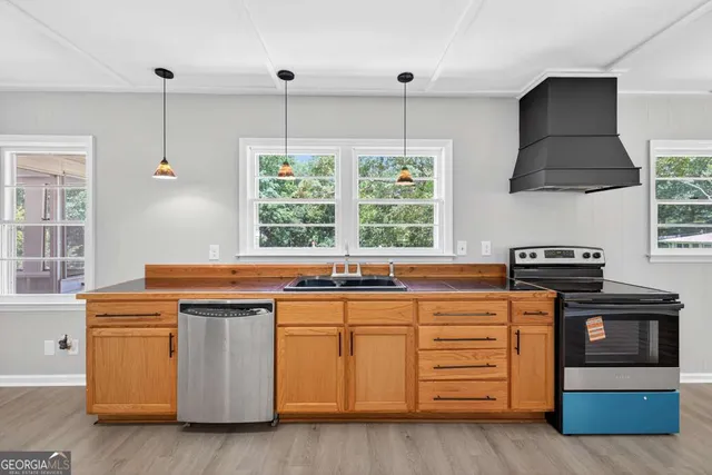 a view of a kitchen and an empty room with wooden floor
