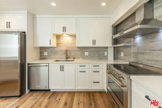 a kitchen with granite countertop white cabinets and stainless steel appliances