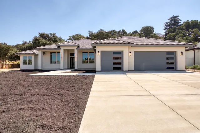a front view of a house with a garden and trees