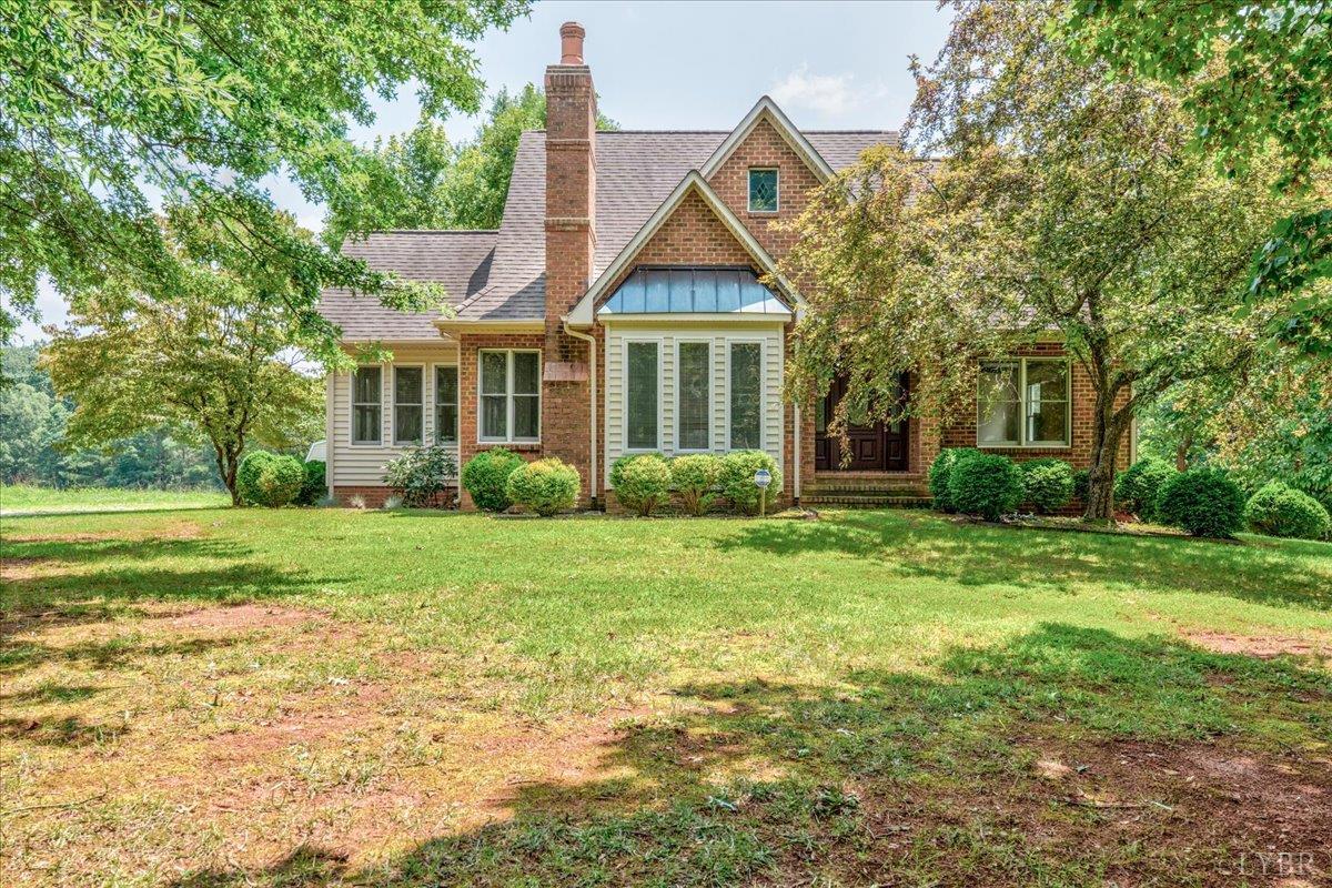 a view of a house next to a big yard and large trees