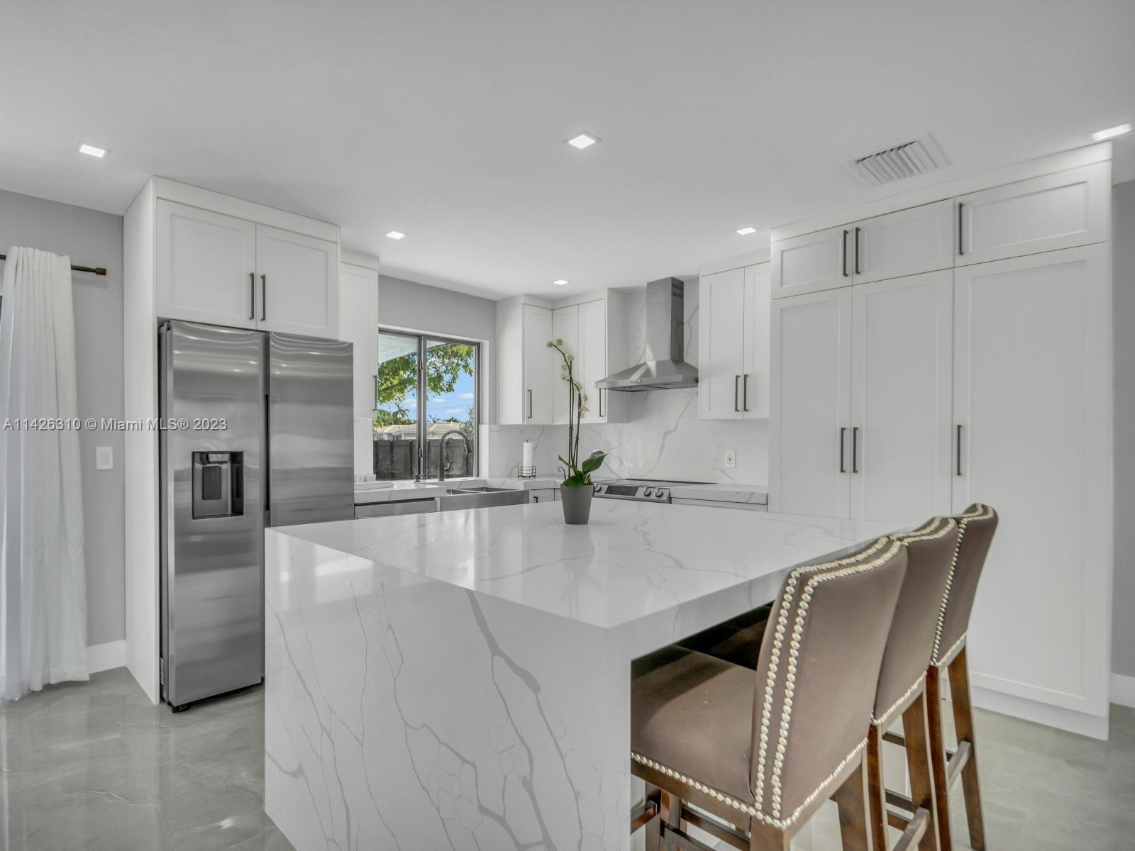 9670 Southwest 17th Street Miami, FL 33165 - Photo 7 of 17 a kitchen with granite countertop a refrigerator a stove a sink a dining table and chairs