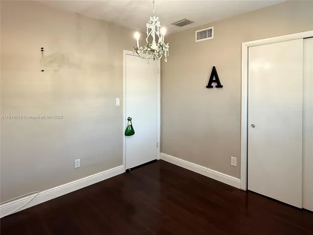 a view of a hallway with wooden floor and a chandelier