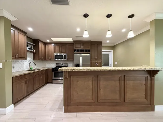 a large kitchen with stainless steel appliances kitchen island granite countertop a stove and a sink