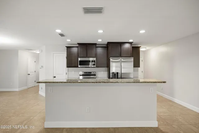 a kitchen with stainless steel appliances granite countertop a sink a stove top oven a counter space and cabinets