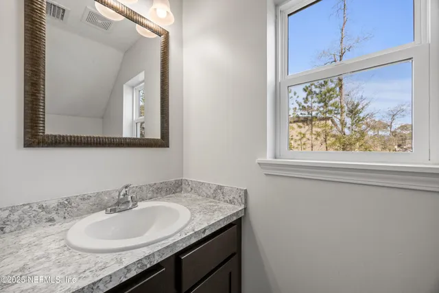 a bathroom with a granite countertop sink and a mirror