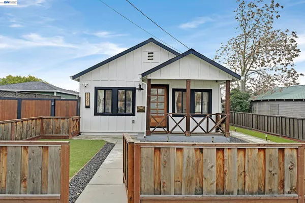 a view of house with a small yard and wooden fence