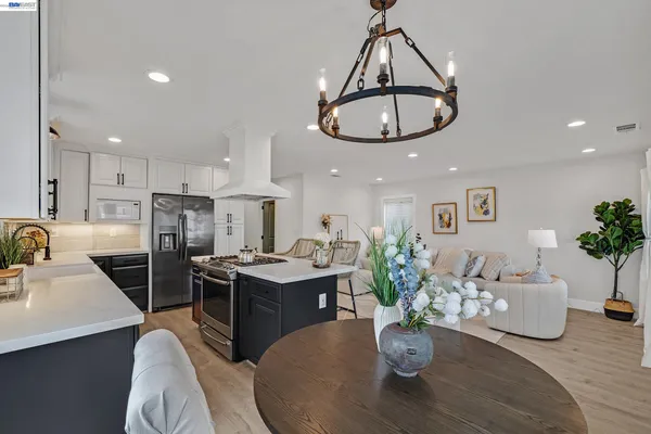 a kitchen with stainless steel appliances a dining table chairs stove refrigerator and cabinets