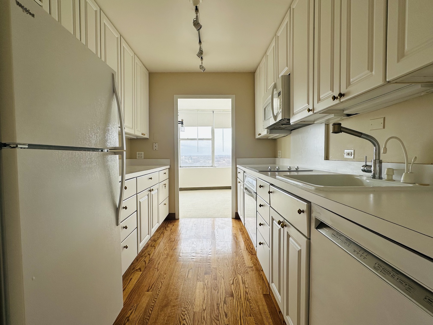 5757 North Sheridan Road, Unit 17H Chicago, IL 60660 - Photo 8 of 25 a kitchen with granite countertop a refrigerator a sink and dishwasher with white cabinets