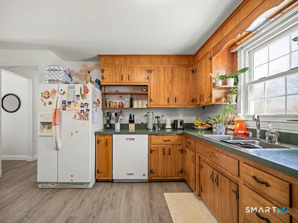 a kitchen with stainless steel appliances granite countertop a refrigerator a sink dishwasher a stove and white countertops with wooden floor