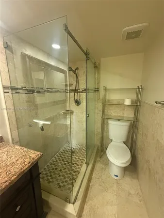 a bathroom with a granite countertop toilet a sink and a shower