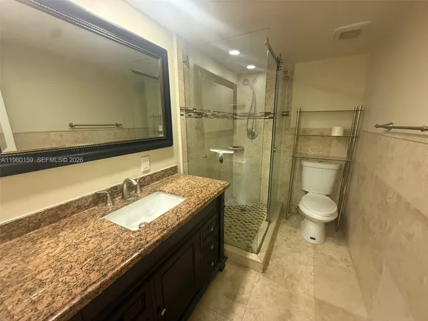 a bathroom with a granite countertop sink toilet a mirror and shower