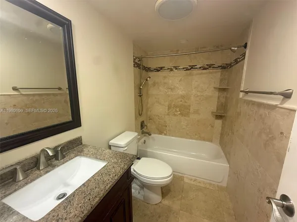 a bathroom with a granite countertop sink toilet mirror vanity and bathtub