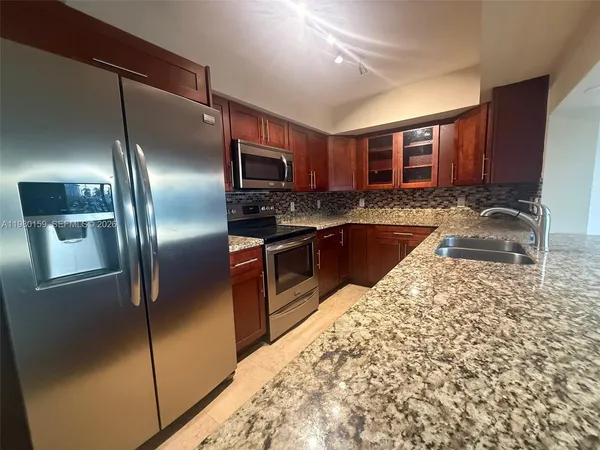 a kitchen with stainless steel appliances granite countertop a refrigerator a oven a sink with granite countertops and a view of living room