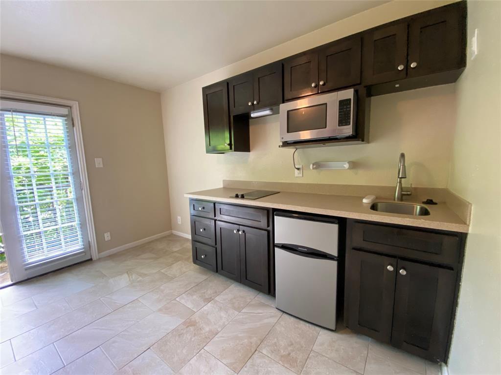 2402 Rio Grande Street, Unit 4 Austin, TX 78705 - Photo 3 of 5 Compact kitchen area featuring dark wood-finish cabinetry, a stainless steel microwave, and a stainless steel mini-refrigerator