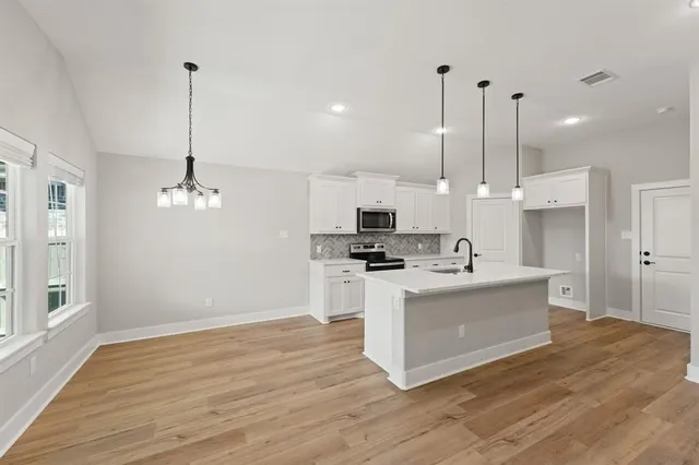 a kitchen with stainless steel appliances kitchen island a white cabinets and a chandelier