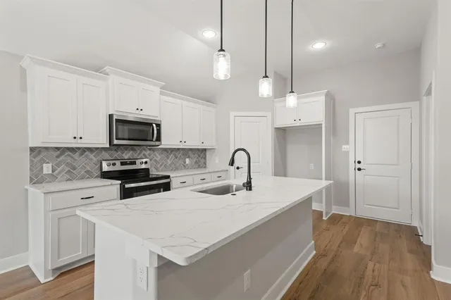 a kitchen with stainless steel appliances a stove a sink a microwave a center island and cabinets