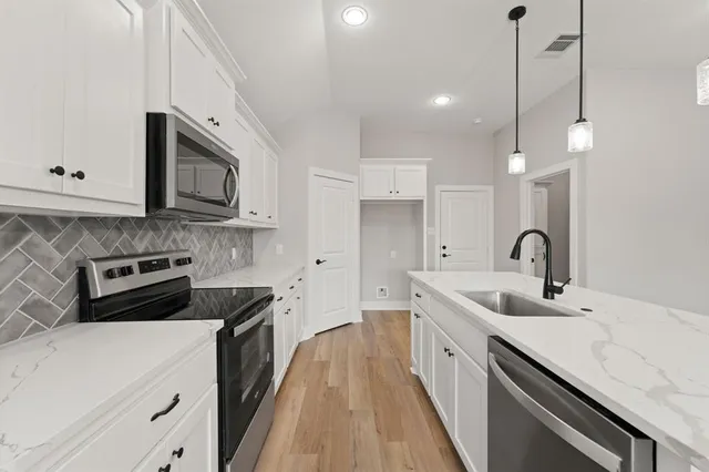 a kitchen with stainless steel appliances granite countertop a sink a stove and a refrigerator