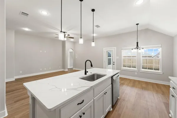 a kitchen with a sink chandelier and wooden floor