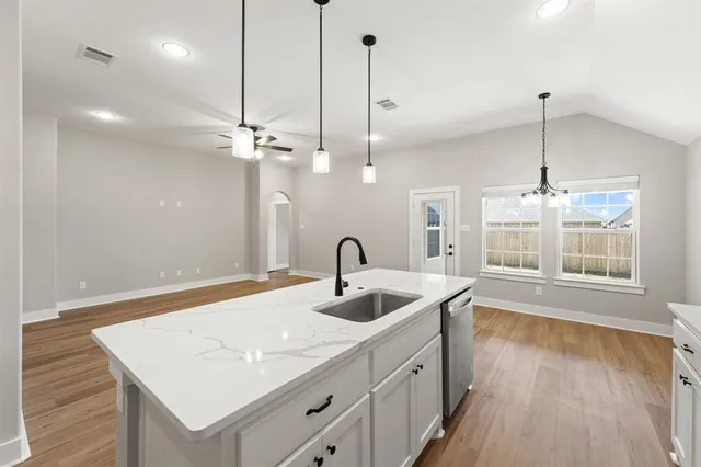 a kitchen with a sink chandelier and wooden floor