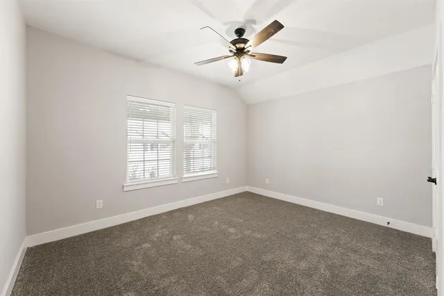 an empty room with chandelier fan and windows